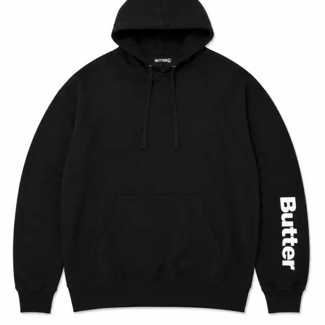 Flat lay of a black pullover hoodie with white Butter text printed vertically on the left sleeve.