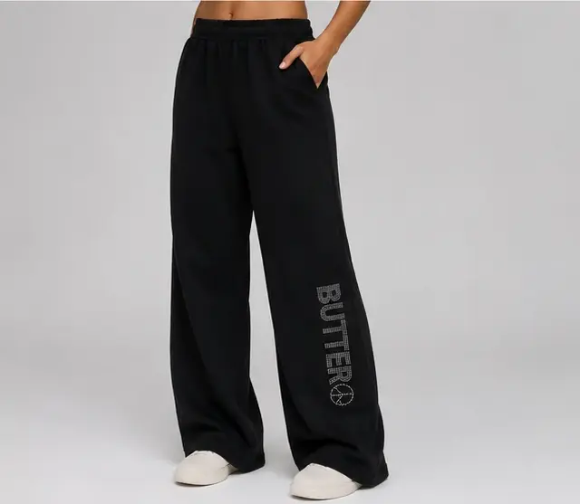 Black wide-leg sweatpants with a rhinestone 'BUTTER' logo on the left leg.