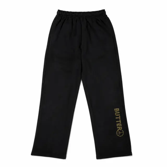 Flat lay of black wide-leg sweatpants featuring a gold 'BUTTER' and peace sign logo on the lower left leg.