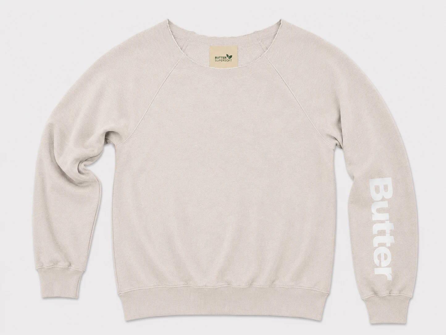 Flat lay of a cream/off-white off-the-shoulder sweatshirt featuring white 'Butter' text on the left sleeve and a 'Butter Super Soft' neck tag.