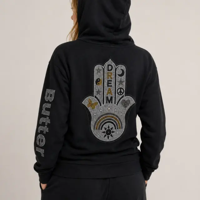 Rear view of a model wearing a black hoodie with the large Hamsa hand graphic visible on the back.