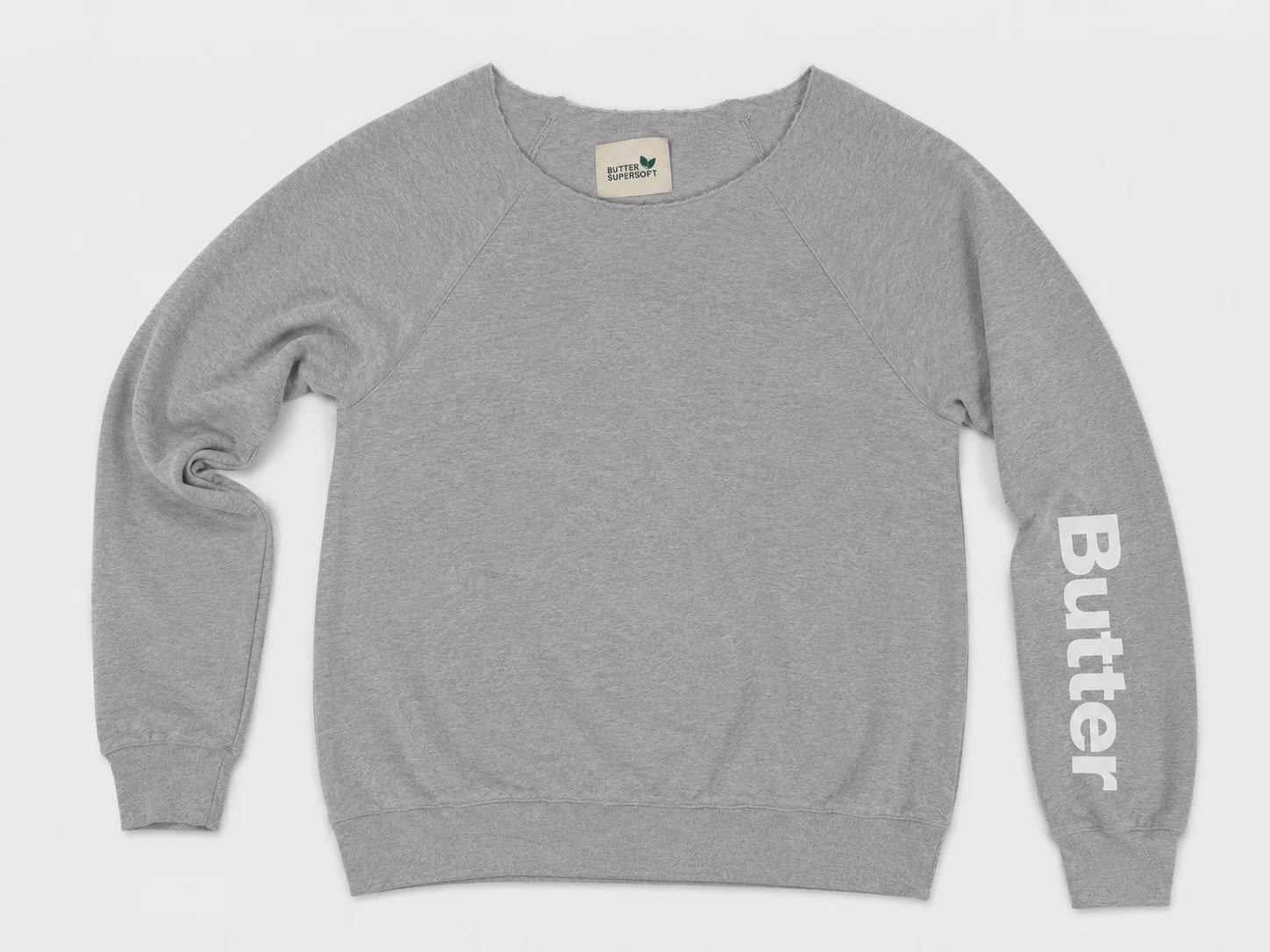 Flat lay of a heather grey off-the-shoulder sweatshirt featuring white 'Butter' text on the left sleeve and a 'Butter Super Soft' neck tag.