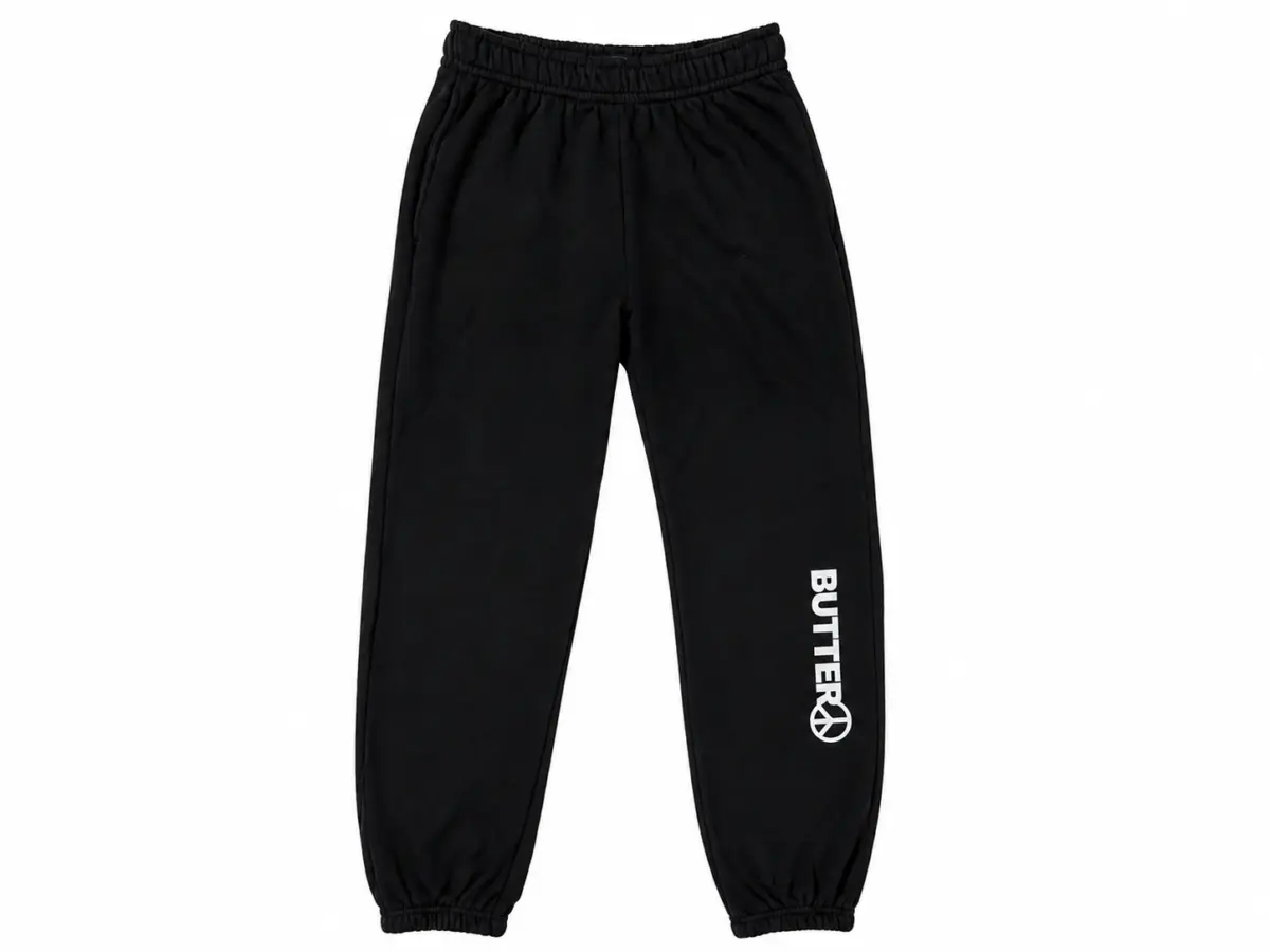 Black sweatpants with a white vertical logo and peace sign graphic on the lower left leg, featuring an elastic waistband and elasticated cuffs.
